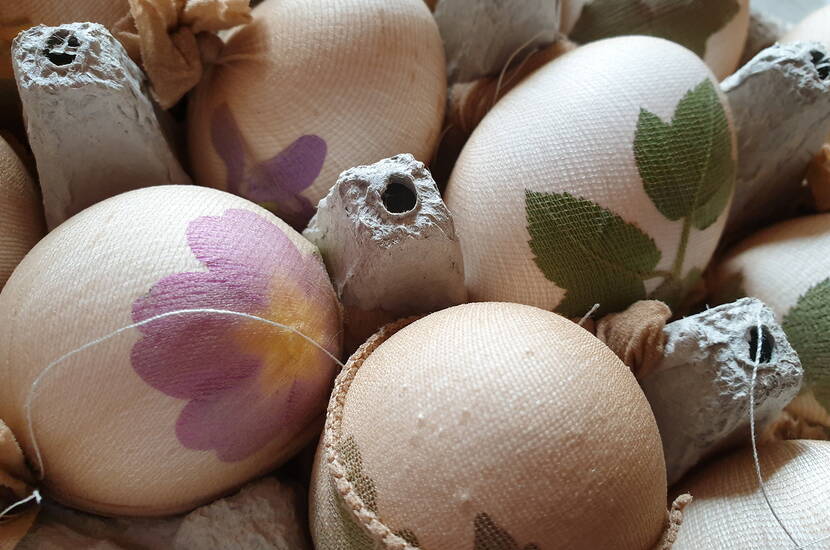 Zoom: Fiori e foglie bianche in filigrana adornano le uova di Pasqua tinte, che decorano la tavola del brunch di Pasqua in tonalità brillanti di viola, rosa e fucsia. A seconda della consistenza dei gusci d'uovo, i colori vanno dal sottile al brillante e creano un effetto wow.