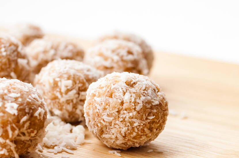 Mélangez tous les ingrédients, formez des boules, roulez-les dans les flocons de noix de coco et placez-les sur une plaque de cuisson recouverte de papier sulfurisé. Préchauffez le four à 150°C et faites cuire les biscuits pendant 25-30 minutes.