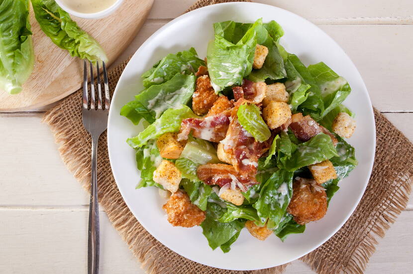 Er besteht aus Lattich, Croûtons, Parmesan und einem speziellen Dressing.