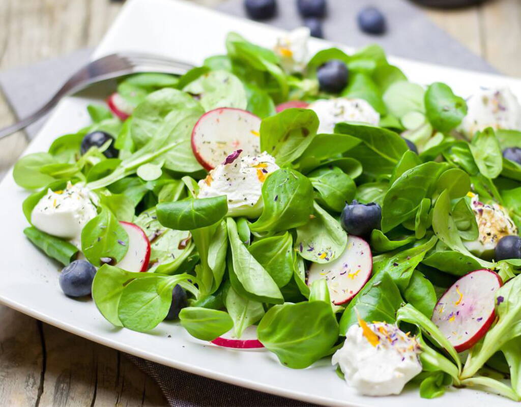 N'ont-elles pas l'air absolument accueillantes, les baies bleu foncé bien pleines qui ornent la salade de rampon fraîche? Une salade saine et savoureuse avec des rondelles de radis croquantes, des myrtilles pauvres en calories et riches en vitamines et de la ricotta crémeuse.