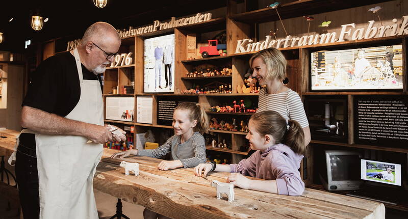 Wer hatte eigentlich die Idee, eine Holzkuh zu schnitzen und ihr rote Flecken anzumalen? Wie ist sie weltweit so beliebt geworden? Wie wird das süsse Ding hergestellt und was bedeutet, sie sei «von Hand gemacht» und «nachhaltig»?