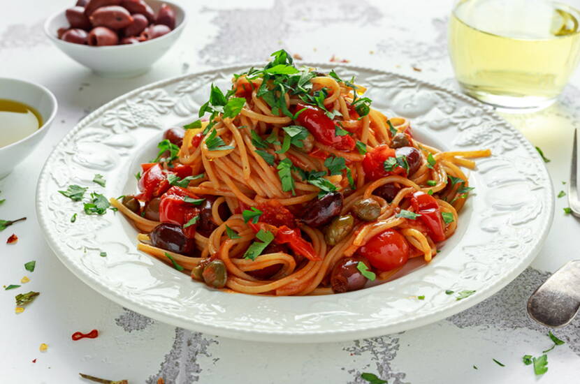 Die Pasta alla Puttanesca ist die Königsdisziplin gestresster italienischer Hausfrauen. Schnell Zwiebeln und Knoblauch schälen, hacken und in Olivenöl andünsten. In der Zwischenzeit die Pasta aufsetzen und al dente kochen.