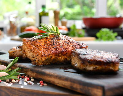 Carne grigliata con rosmarino e spezie Pezzi di carne grigliati con rosmarino su tagliere di legno – la carne cotta si conserva 2-3 giorni in frigorifero e deve essere riscaldata ad almeno 70°C