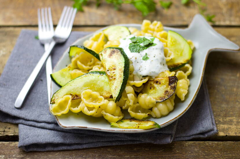 Questa variante leggera è ideale per un pranzo estivo. Mentre la pasta cuoce al dente, tagliare le zucchine a fette sottili e saltarle velocemente in padella con poco olio. Mescolare con la buccia grattugiata e il succo di un limone o di una limetta, versare sulla pasta e aggiustare di sale e pepe. Lo schizzo di yogurt dà al piatto un tocco in più.