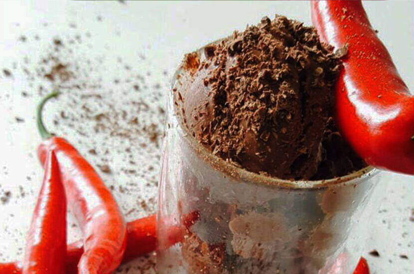 Die Reismilch mit dem Kakaopulver erhitzen, jedoch nicht zum Kochen bringen. Mit dem Schneebesen glattrühren und auskühlen lassen. Den Sojarahm steif schlagen und mit dem Agavendicksaft und den Schokoladenstückchen unter die Milch-Kakaomasse mischen. Zum Schluss das Chilipulver zufügen und alles in einem Behälter über Nacht einfrieren lassen.